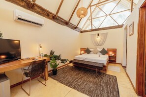 A bedroom with a bed, bedside tables, a desk with a chair, a television, and a large window. - Tay beach hotel - Tayrona (Santa Marta)