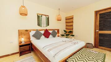 Un dormitorio con una cama de madera, lámparas de noche, un tapiz en la pared y un banco tejido.