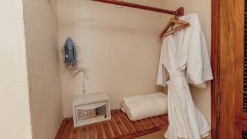 A small, enclosed bathroom with a wooden bench, a towel rack, and a wall-mounted heater.