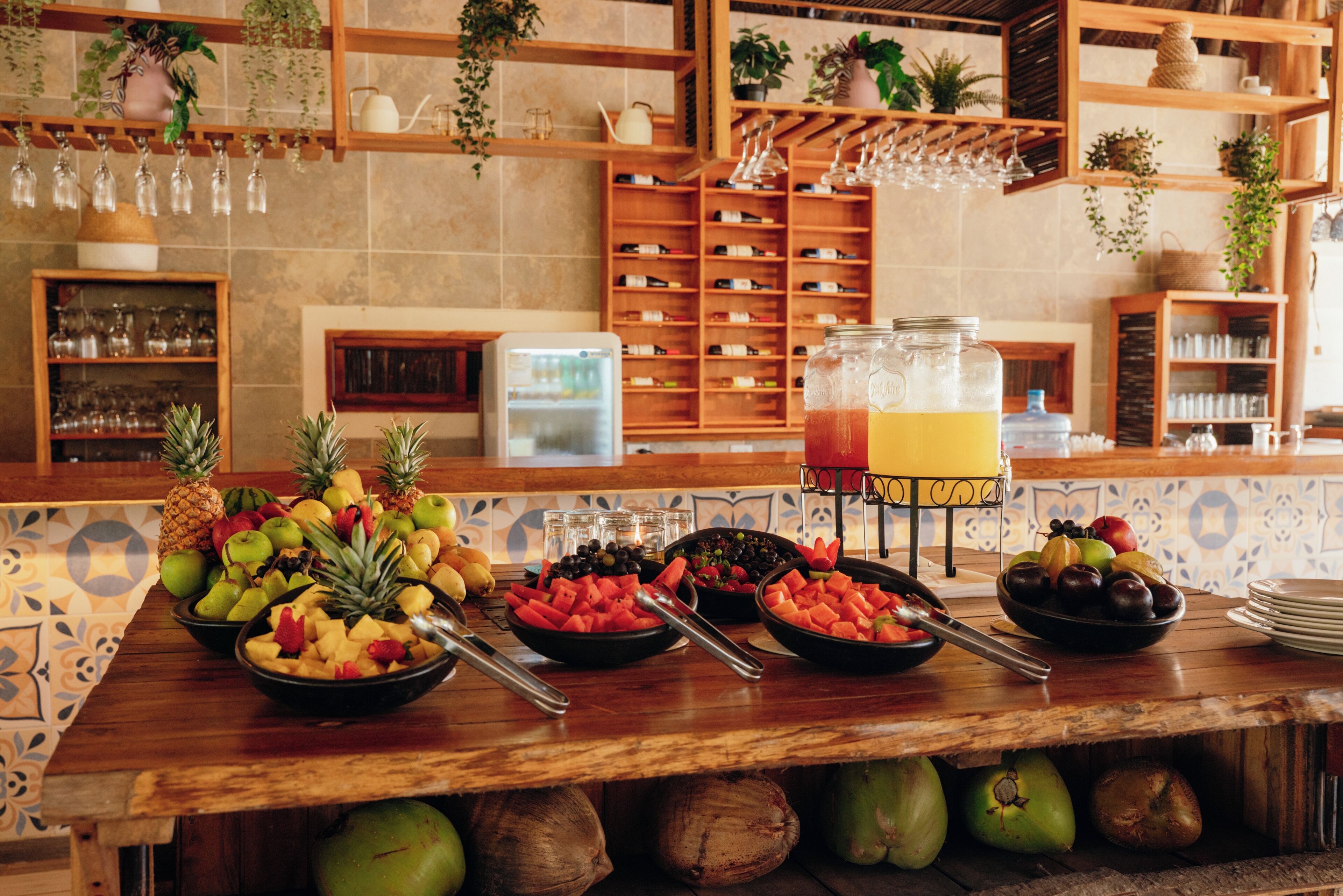 A buffet with a variety of fruits and a juice dispenser.