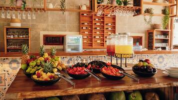 A buffet with a variety of fruits and a juice dispenser.