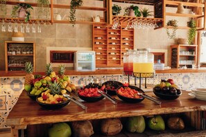Un bufé con una variedad de frutas y un dispensador de zumo.