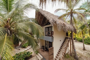 A two-story building with a thatched roof, surrounded by palm trees.