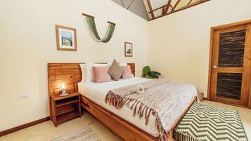Un dormitorio con cama de madera, mesitas de noche, una planta colgante y una ventana con persianas.