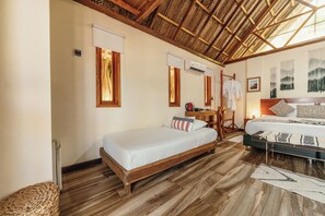 Una habitación con dos camas, suelo de madera, techo con diseño trenzado y un aire acondicionado instalado en la pared.