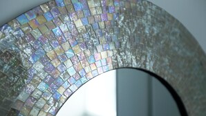 Ein runder Spiegel mit Mosaikrahmen.