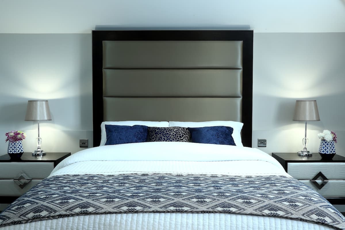 Una habitación de hotel moderna con una cama grande, dos mesitas de noche y un cabecero.