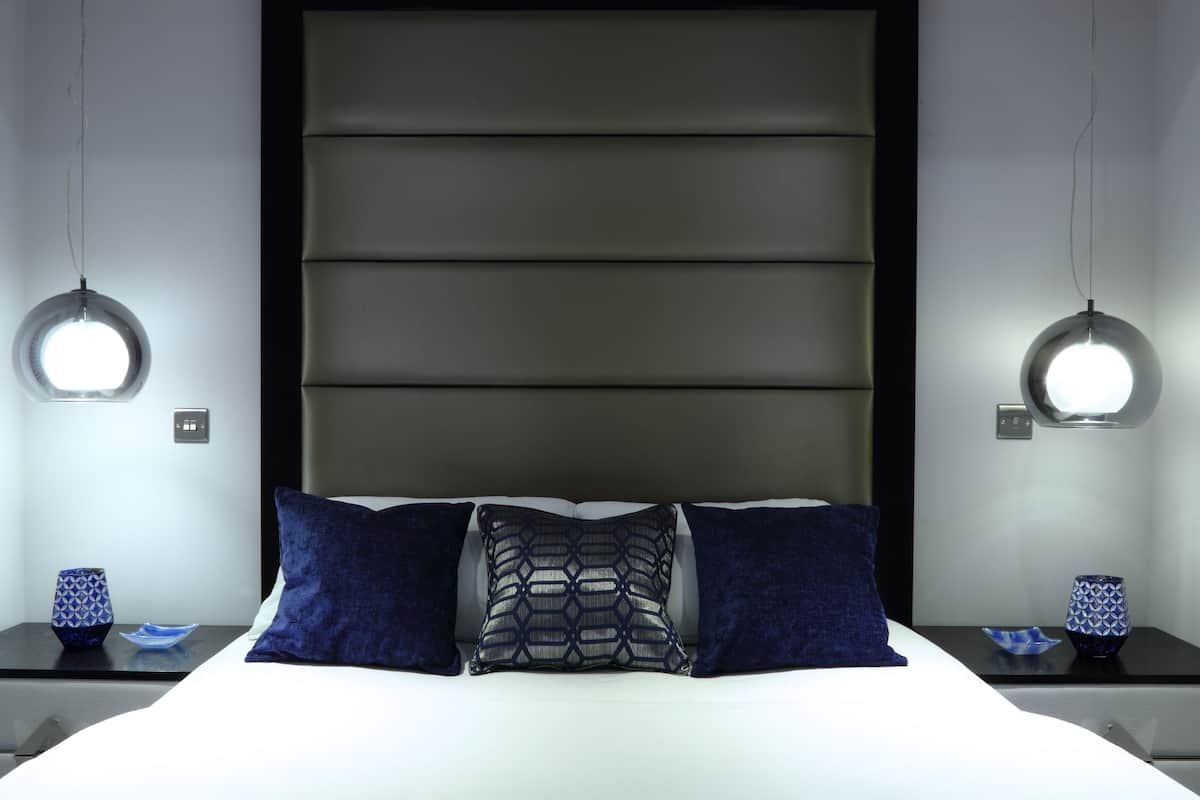 Un dormitorio moderno con una cama grande, dos mesitas de noche y lámparas colgantes.
