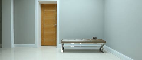 A hallway with a wooden door and a bench.