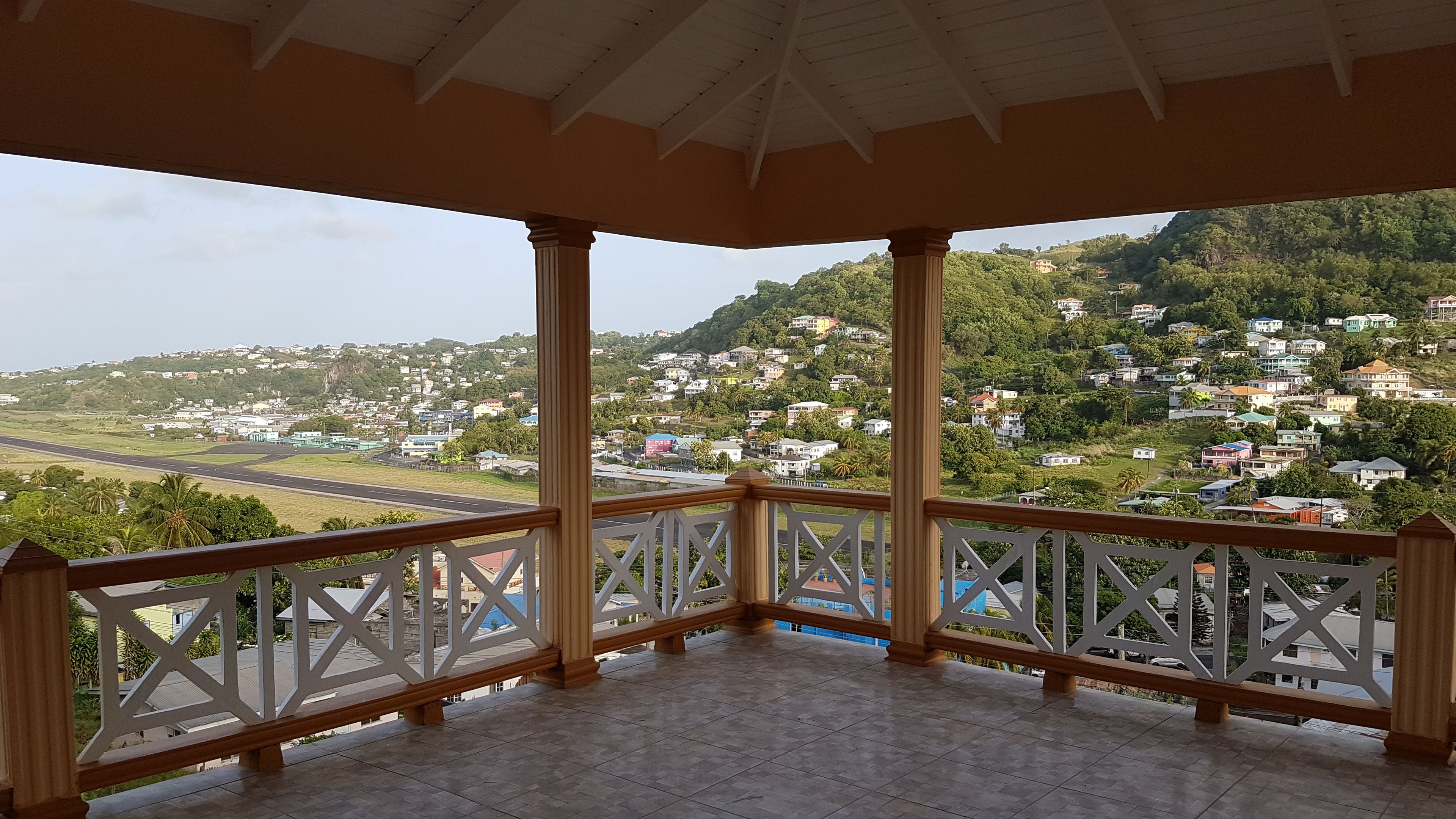 Varanda coberta com vista para uma área residencial e uma rua.