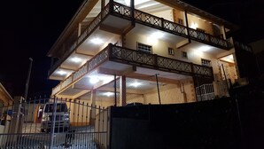 Un edificio de varios pisos con balcones y una entrada protegida por una reja.