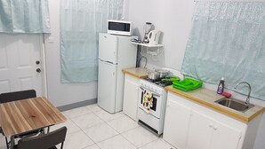 Una cocina compacta con refrigerador, microondas, estufa y pileta.