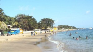 Una playa con gente nadando y caminando por la orilla.
