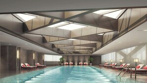A modern indoor swimming pool with multiple lounge areas, a geometric ceiling design, and large windows. - Zhenjiang Marriott Hotel (Zhenjiang)