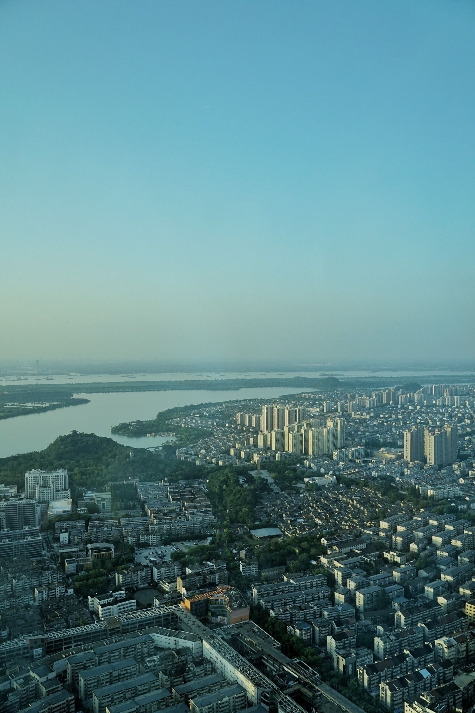 A cityscape with dense urban development, a river, and a distant body of water.