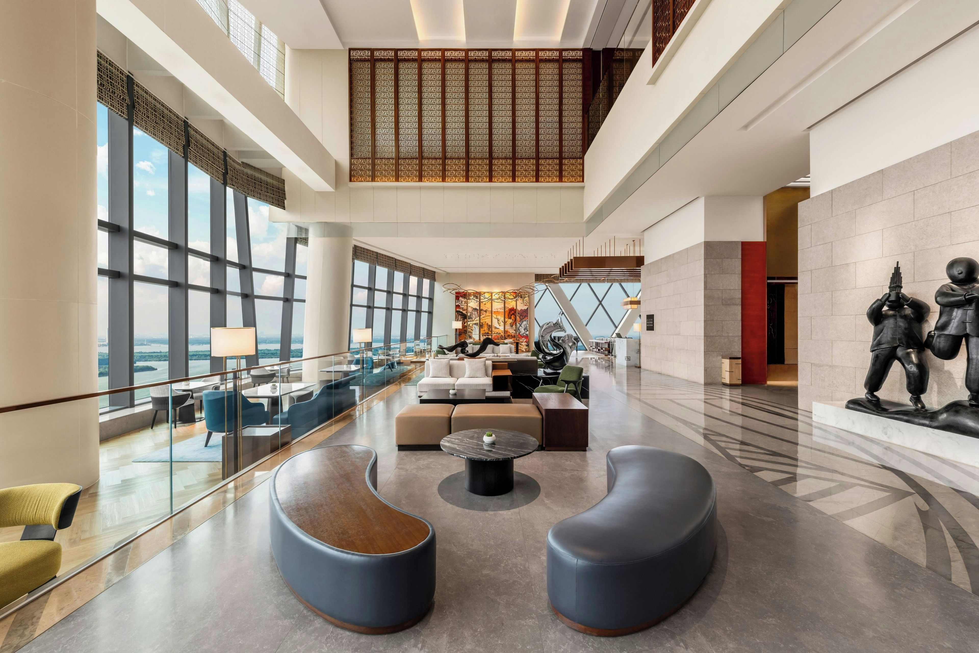 A spacious lobby with a seating area, a large window offering a view, and a statue on the wall.