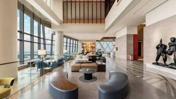 A spacious lobby with a seating area, a large window offering a view, and a statue on the wall.
