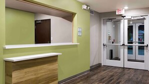 Un área de recepción con una pared verde, un mostrador de madera y una puerta de cristal.