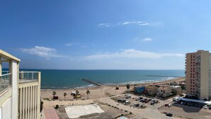 A coastal view with a beach, a pier, and a parking area with cars. - Modern Penthouse Apartment on the Beach (Puig)