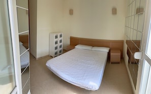 Une chambre à coucher avec un grand lit, une table de chevet, une commode et un miroir.