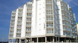 A multi-story hotel with a modern design, featuring balconies on each floor and a prominent entrance with a covered area. - Modern Penthouse Apartment on the Beach (Puig)