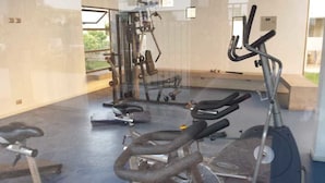 A gym with exercise equipment including a stationary bike, a rowing machine, and weight benches.