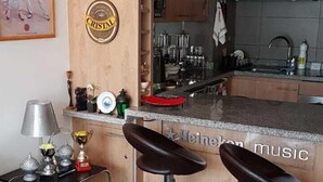 A modern kitchen with a bar area, bar stools, and a wine rack.