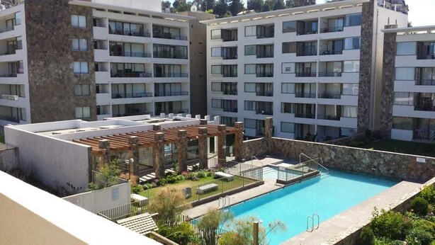 A modern hotel with multiple floors, a rooftop pool area, and a covered outdoor seating area.