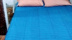A bed with a blue bedspread and two pink pillows in a room with white walls. - Kfe L Hostel (Calarcá)