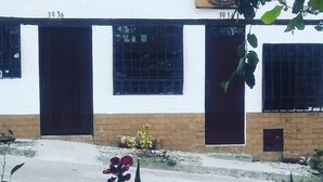 A building with numbered doors and windows, surrounded by plants. - Kfe L Hostel (Calarcá)