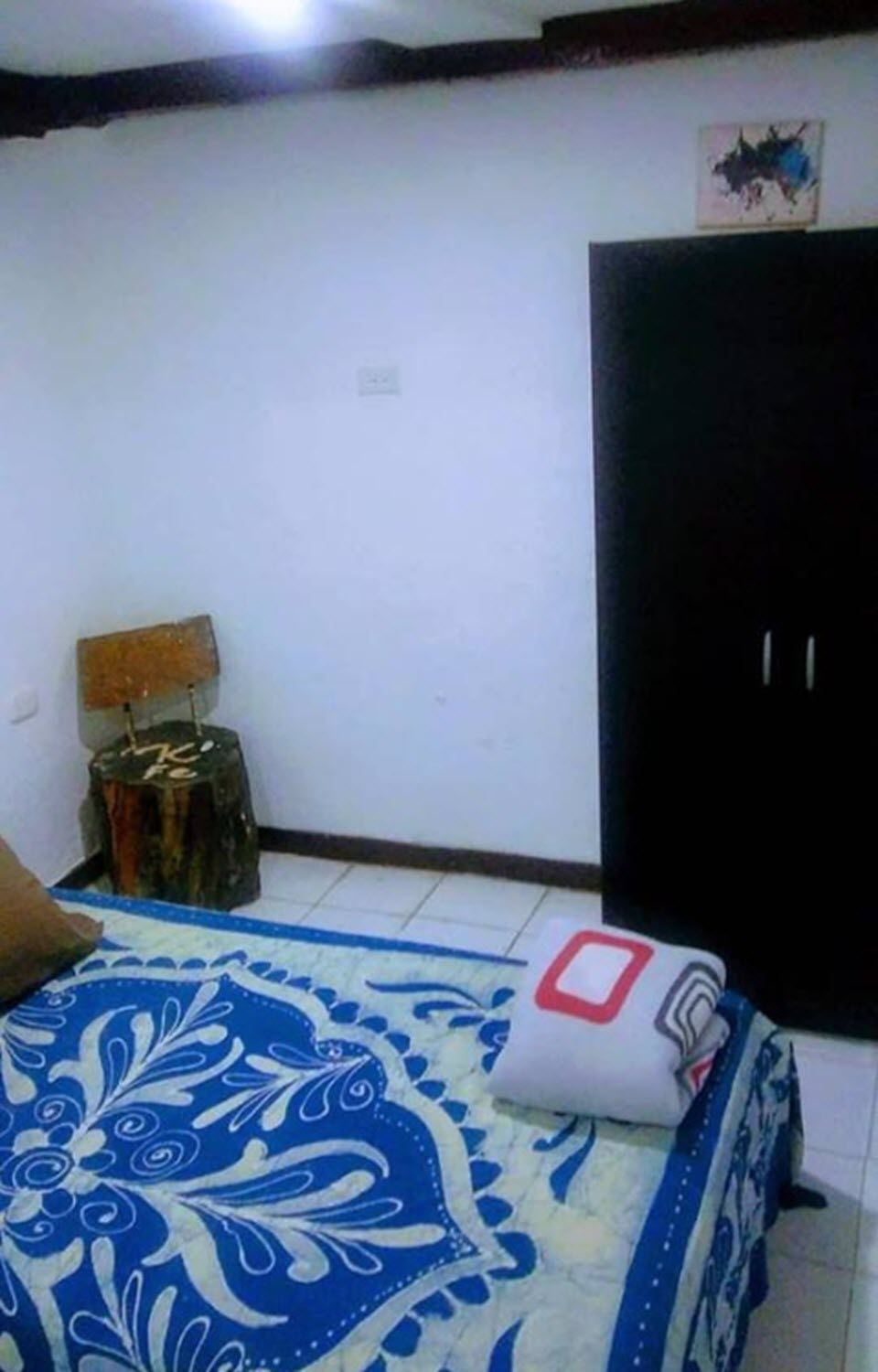 A bedroom with a bed, a nightstand, a lamp, and a wardrobe.