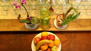 Una mesa de madera con un plato de fruta, dos macetas y un jarrón de vidrio.