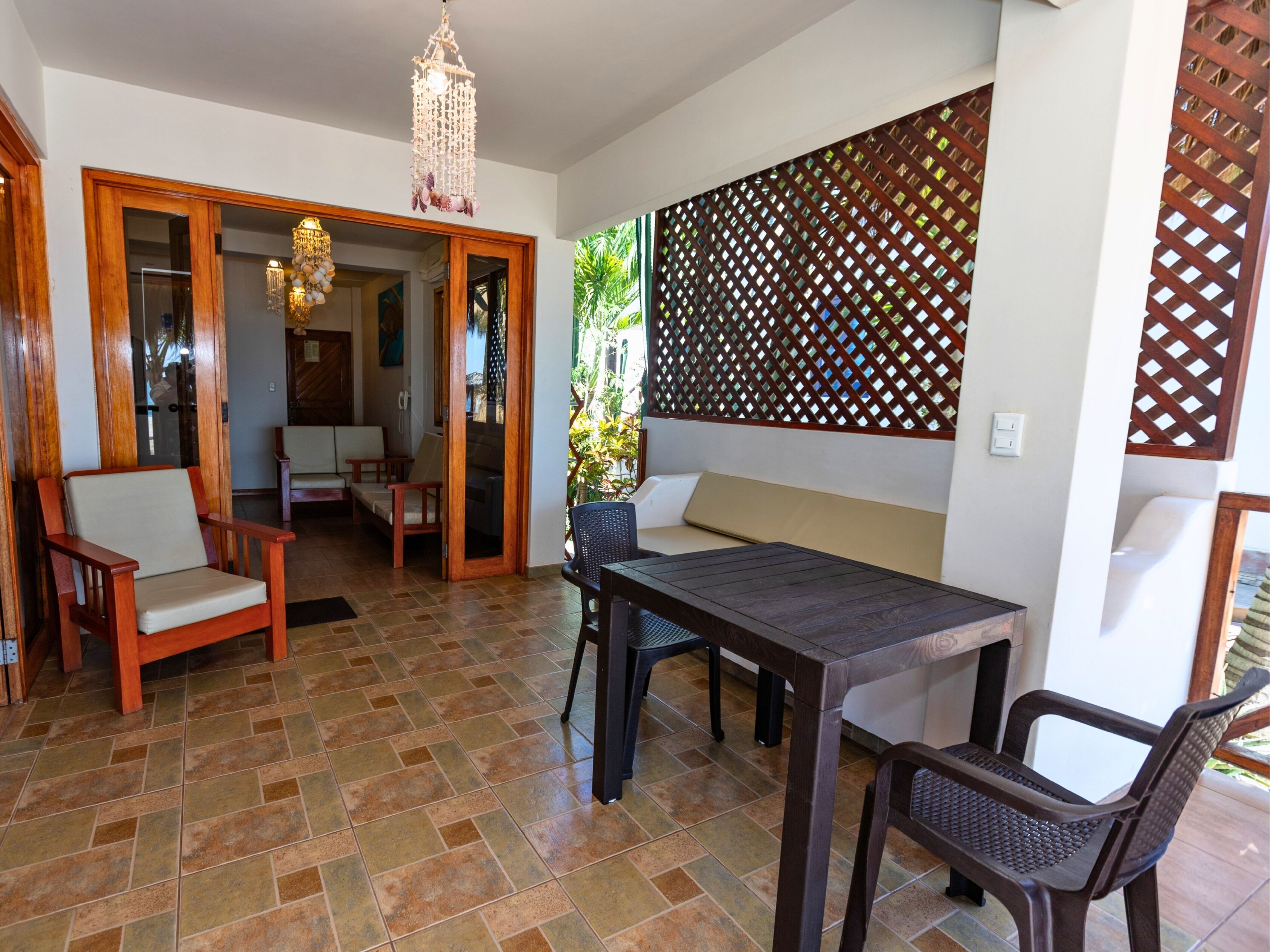 A dining area with a table and chairs, a wooden bench, and a decorative lattice wall.