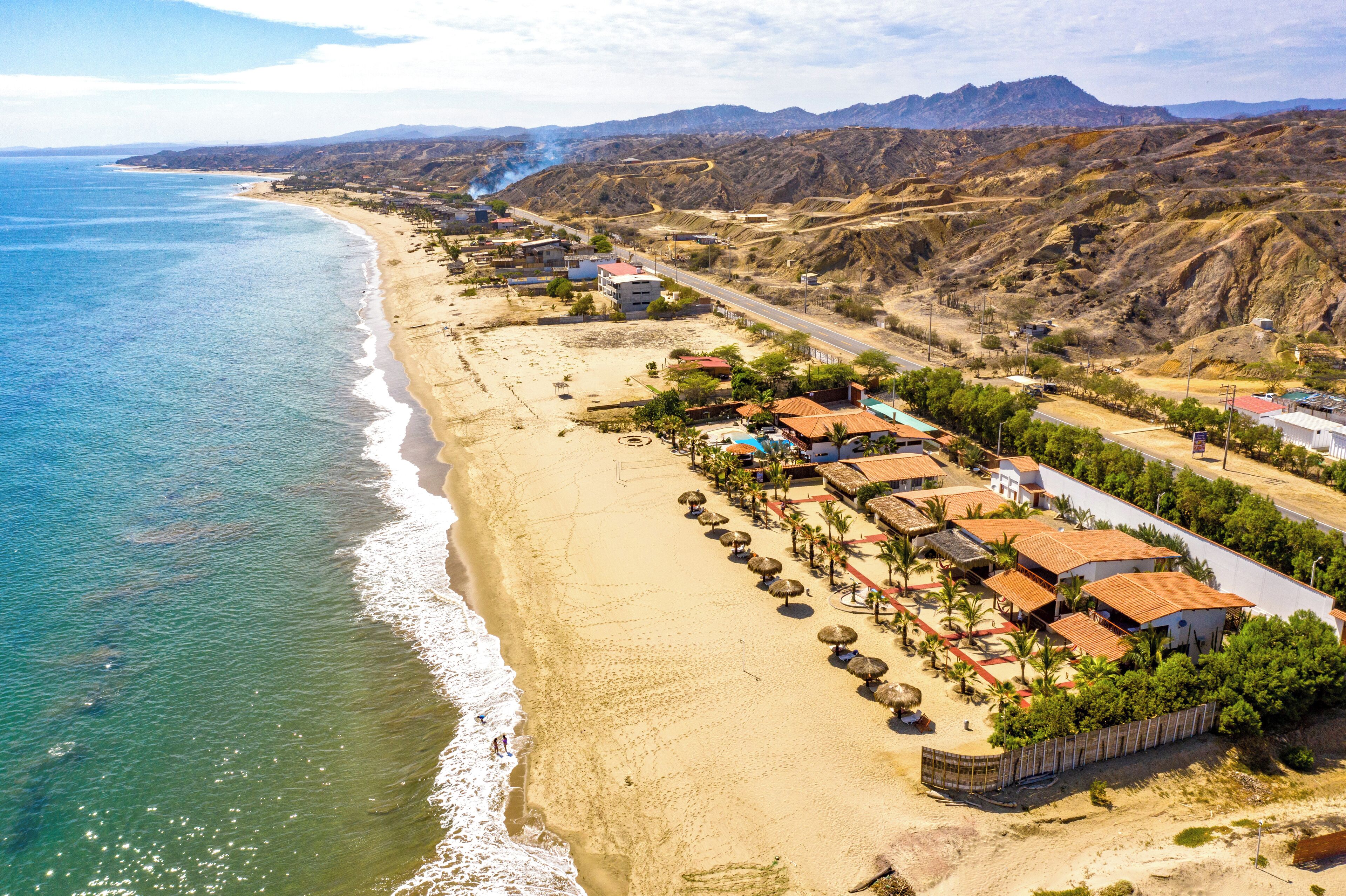 A coastal town with a beach, buildings, and a road.