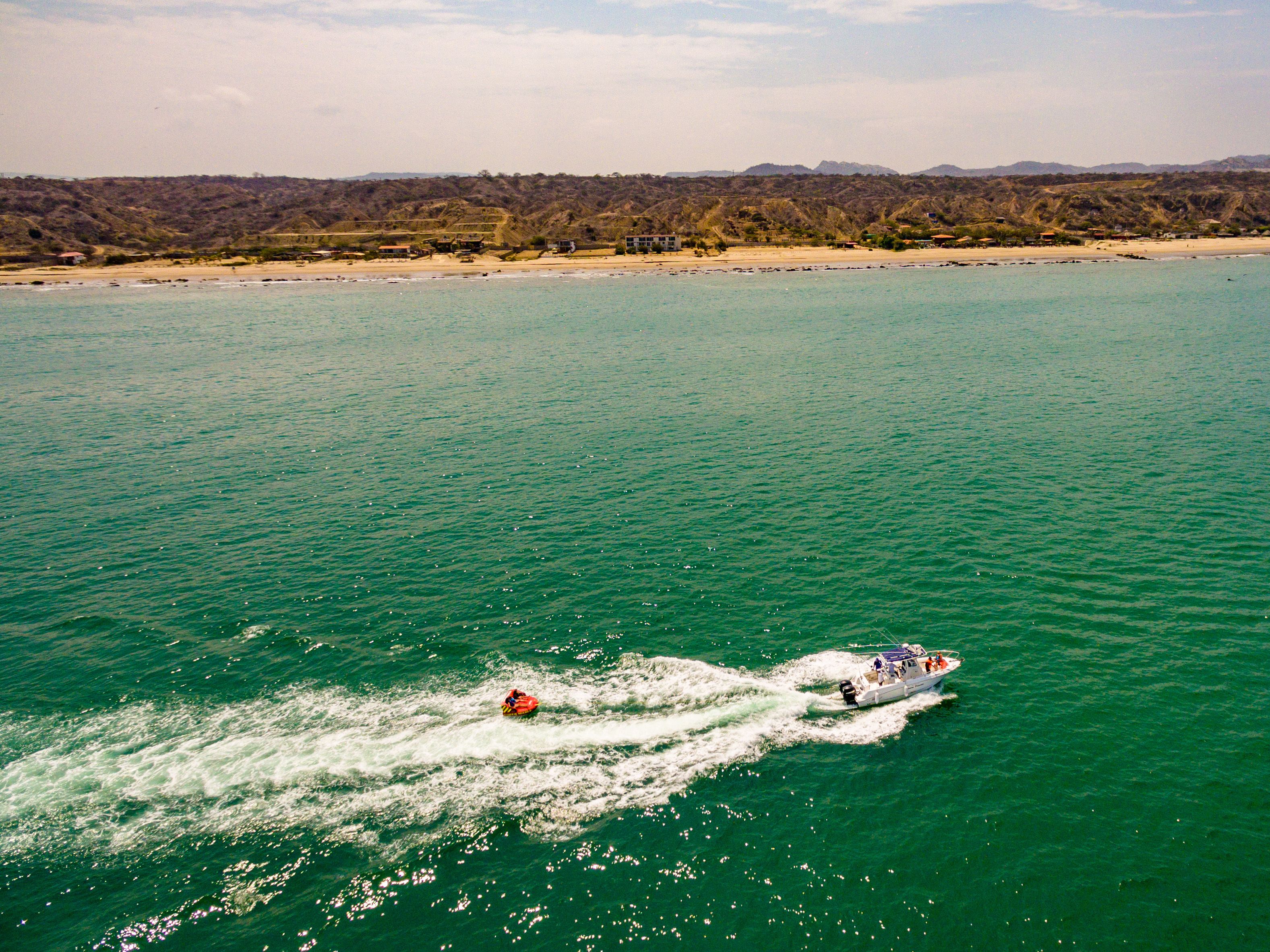 A boat speeding across a turquoise sea with a mountainous backdrop.