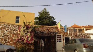 A hotel entrance with a stone facade, a gate, and a flag. - Hotel Raha (Nouakchott)