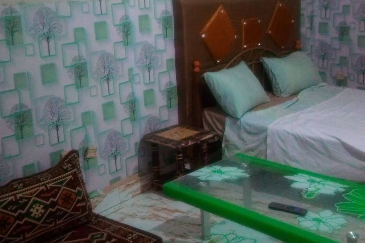 A bedroom with a bed, a sofa, a glass coffee table, and patterned walls.