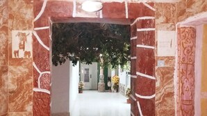 A hallway with a tiled floor, a decorative archway, and potted plants. - Hotel Raha (Nouakchott)
