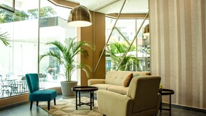 A modern lobby with a sofa, armchairs, a coffee table, and a potted plant. - Hotel Viaggiatore (Cochabamba)