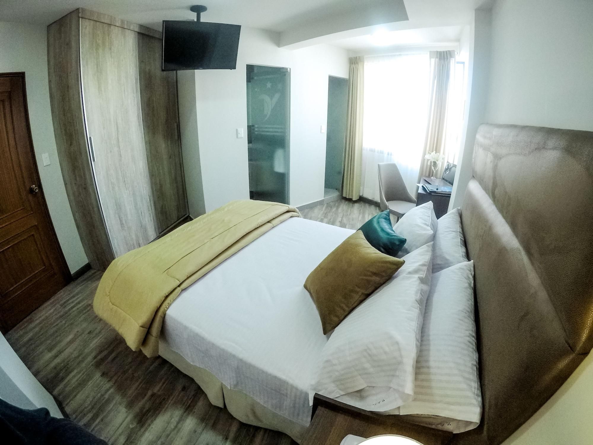 Una habitación de hotel con cama, televisión, escritorio y una silla.