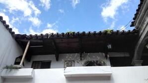 A traditional building with a tiled roof, white walls, and a small balcony with potted plants.