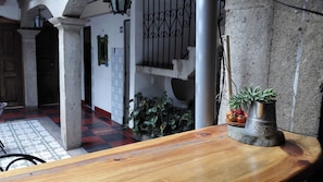 A wooden reception desk with a potted plant and a metal vase. - Hotel Cristal (Antigua Guatemala)