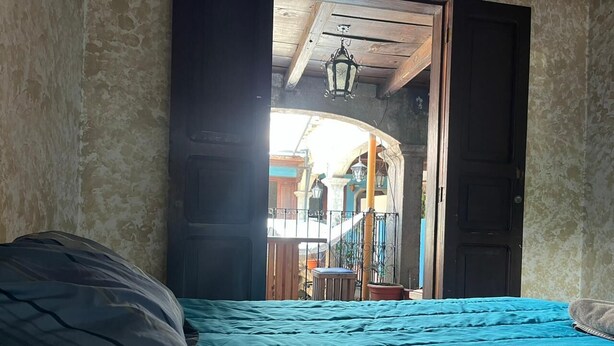 A room with a bed, a door leading to an outdoor area, and a hanging light fixture.
