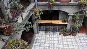 A courtyard with a wooden bench, potted plants, and a tiled floor.