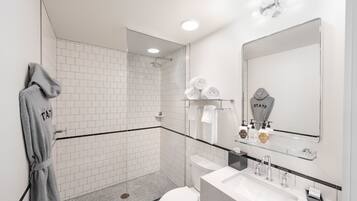 Une salle de bain moderne avec une douche à parois de verre, un lavabo blanc et un grand miroir.
