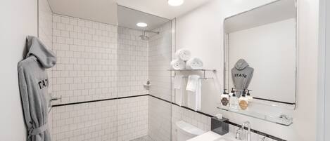 A modern bathroom with a glass shower enclosure, a white sink, and a large mirror.