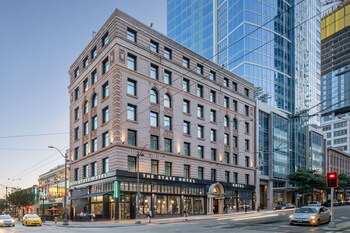 A modern hotel room with a bed, desk, and a large window with curtains. at The State Hotel