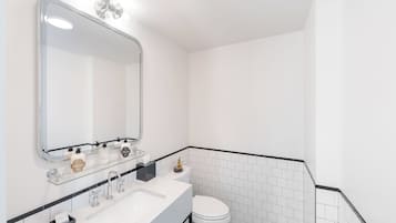 A modern bathroom with a white sink, a large mirror, and a toilet.