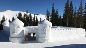 Scultura di neve raffigurante un castello con due torri e un ingresso centrale.