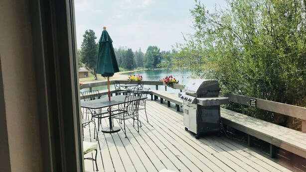 Una terrazza con barbecue, mobili da esterno e vista su un lago.